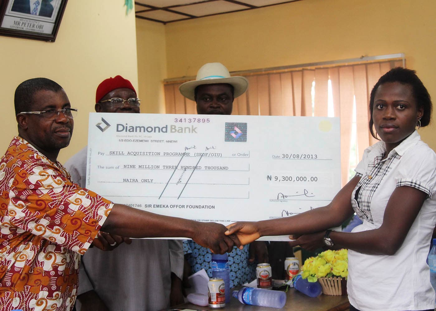 Sir Emeka Offor presenting a cheque to the pioneer graduates of the Foundation skills acquisition scheme at Oraifite, Anambra State